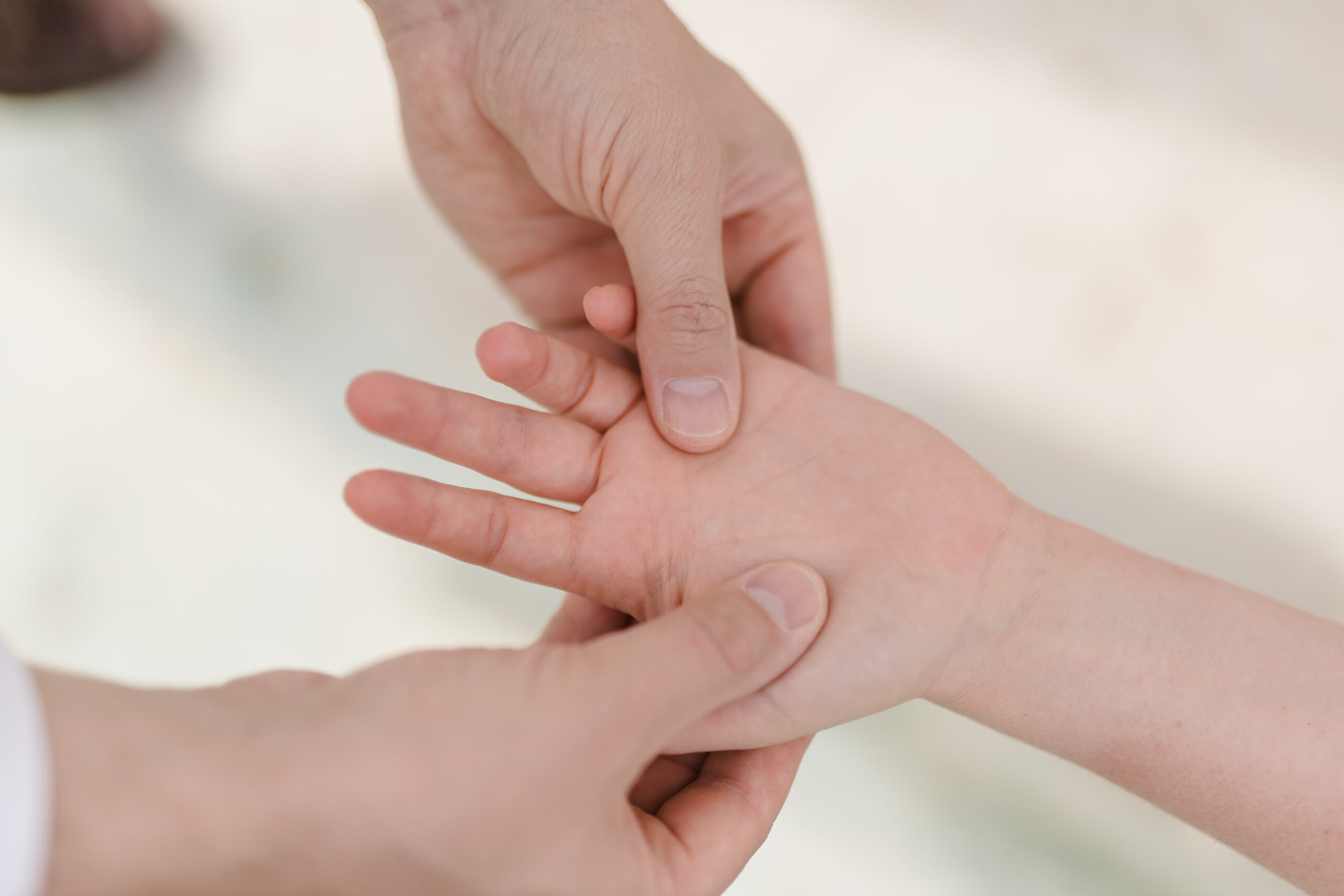Nahaufnahme: Dr. Kyrylenko tastet Handfläche und Fingergrundgelenke einer Patientin ab